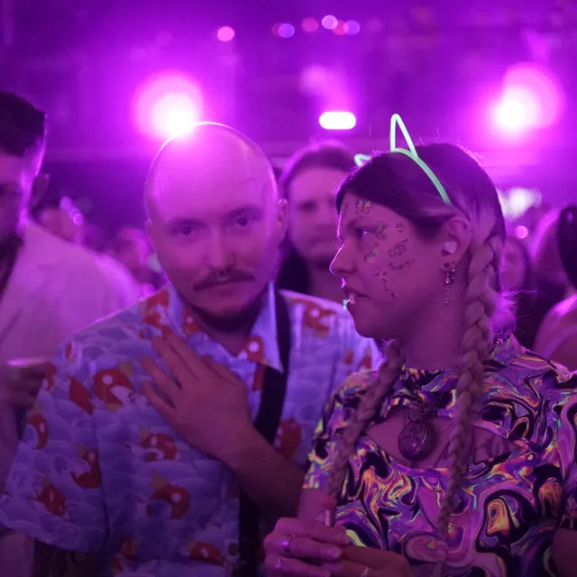 To festivalgæster i farverige skjorter, den ene med lysende katteører.